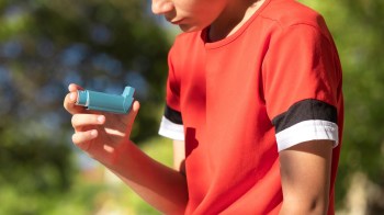 A kid holding a rescue inhaler.