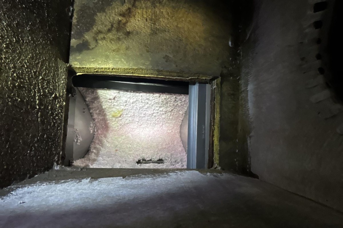 A view into a dark, narrow duct with a visible opening at the end.