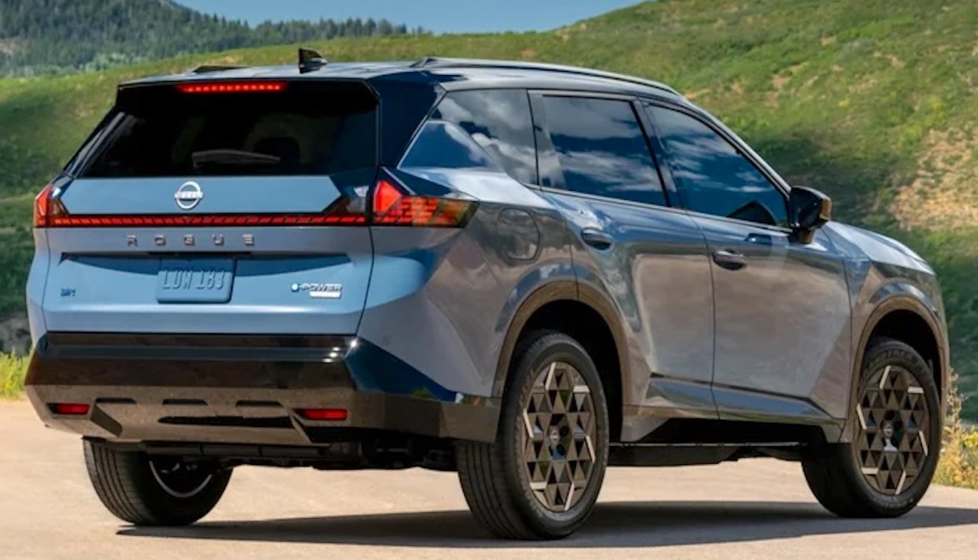 A blue Nissan Rogue parked in a scenic outdoor setting with green hills in the background.