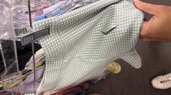 A person holds up a light green checkered fabric in a store display.