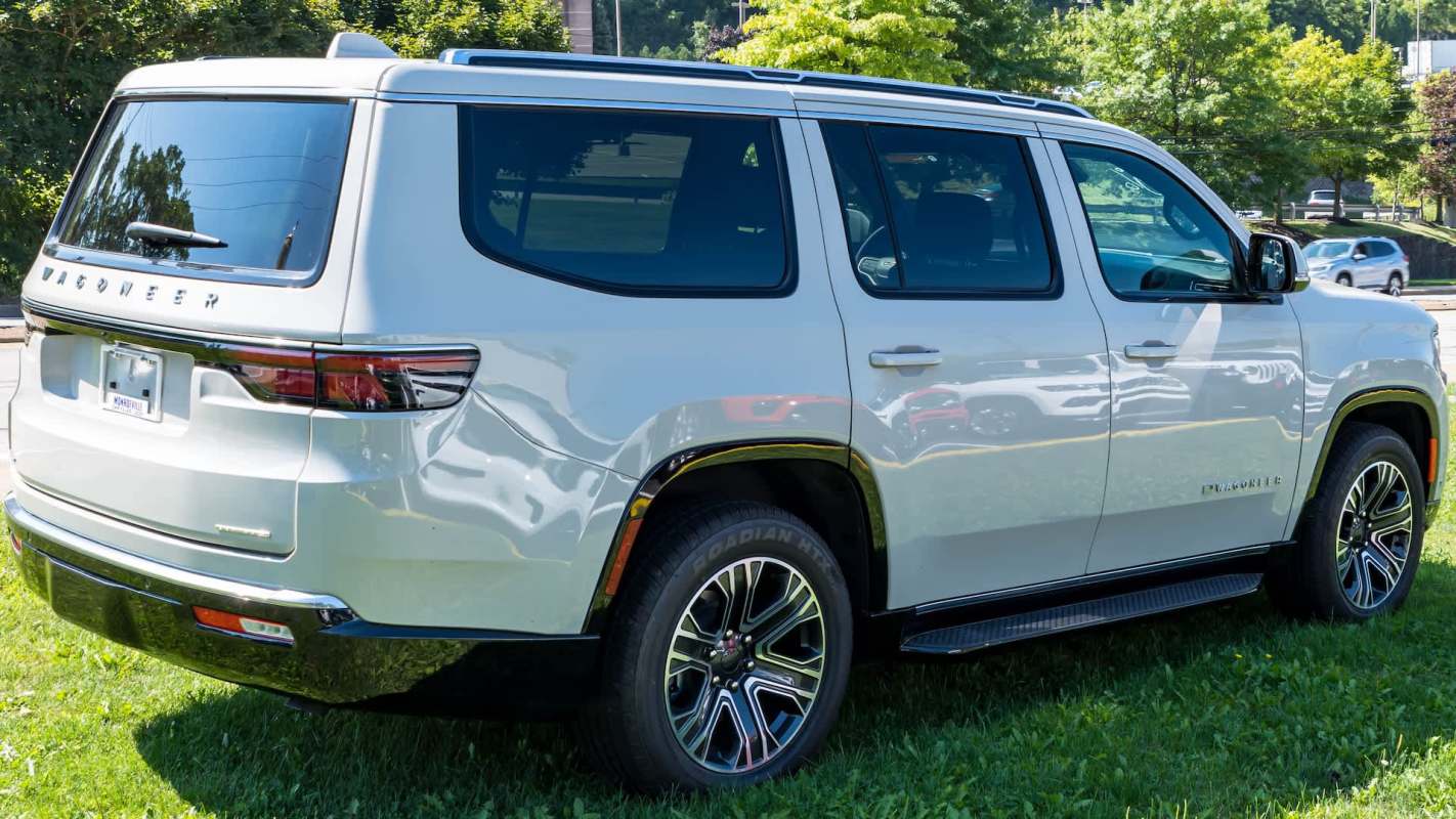A white Jeep SUV parked on grass with "Wagoneer" branding on the side and a shiny metallic finish.