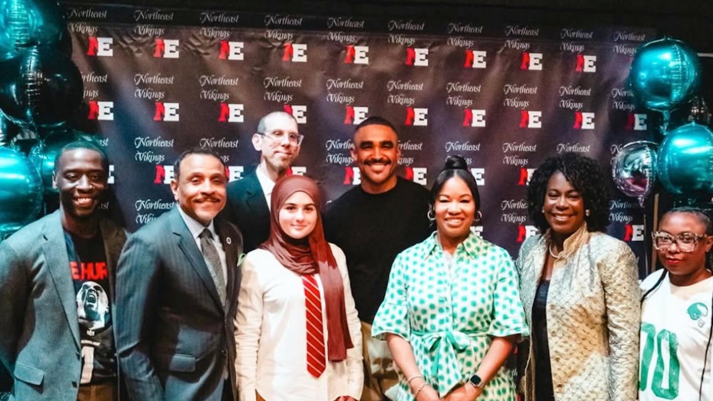 Philadelphia Eagles quarterback Jalen Hurts poses with seven people in front of a backdrop with the text "Northeast Vikings."