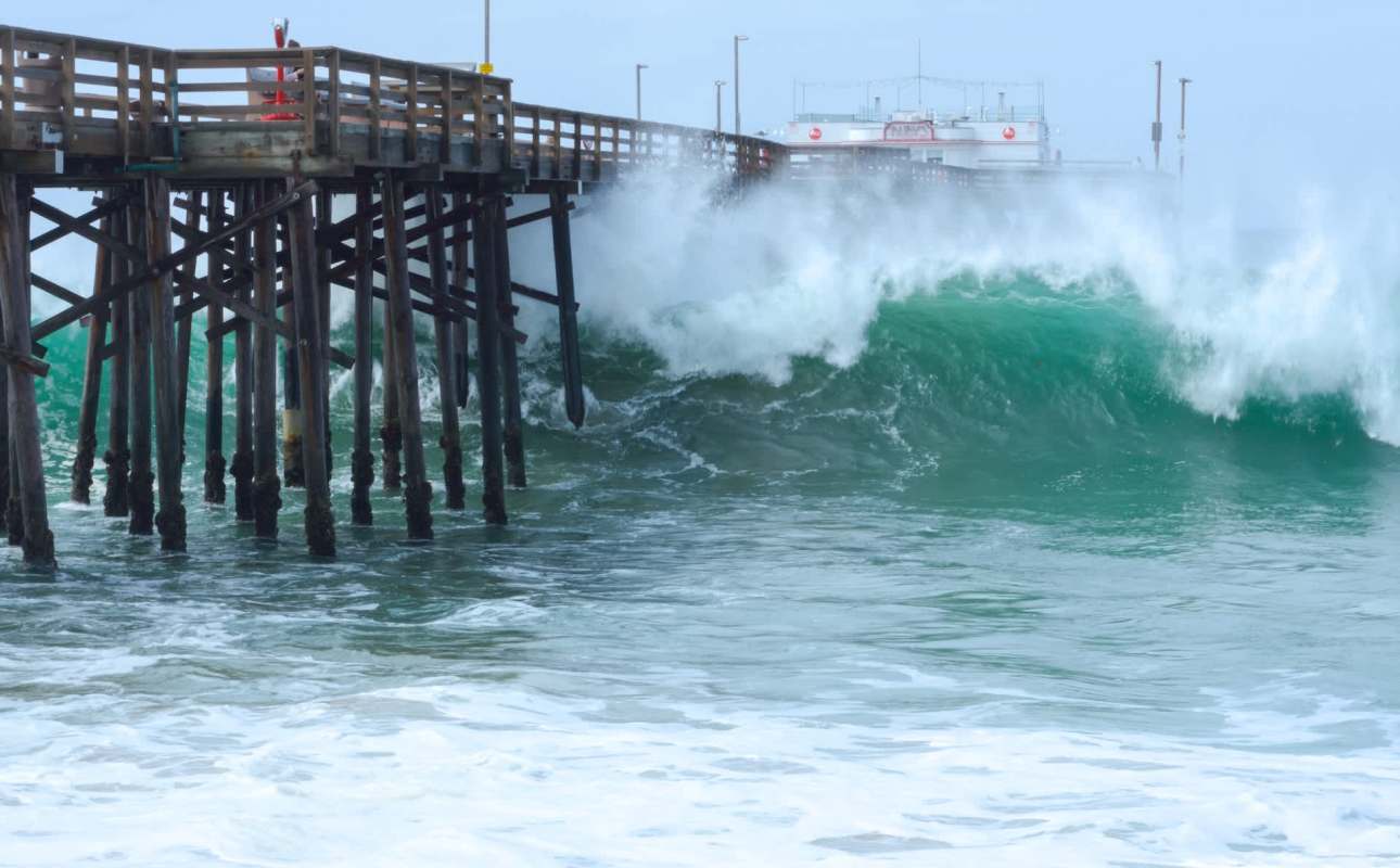 A large wave crashing against a pier.