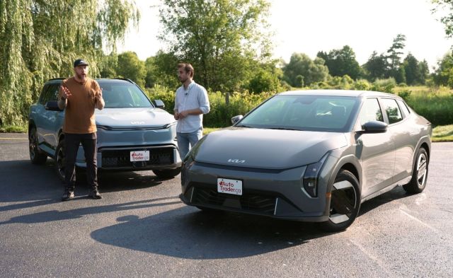 Two people standing near a 2027 Kia EV4 and EV5.