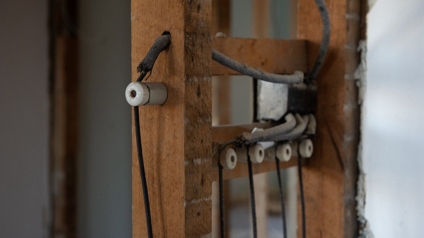 Electrical wiring and ceramic insulators mounted on wooden framing.