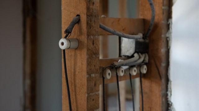 Electrical wiring and ceramic insulators mounted on wooden framing.