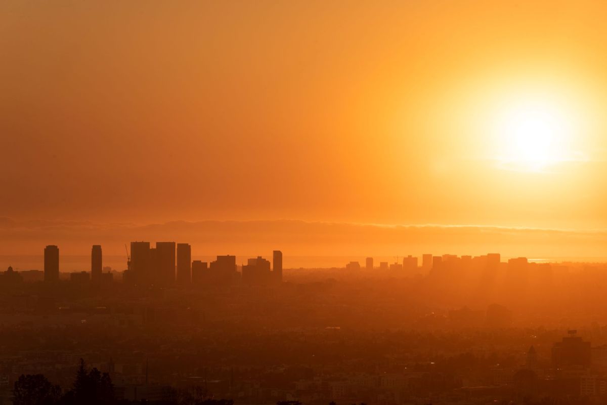 A city skyline silhouetted against a bright orange sunset.