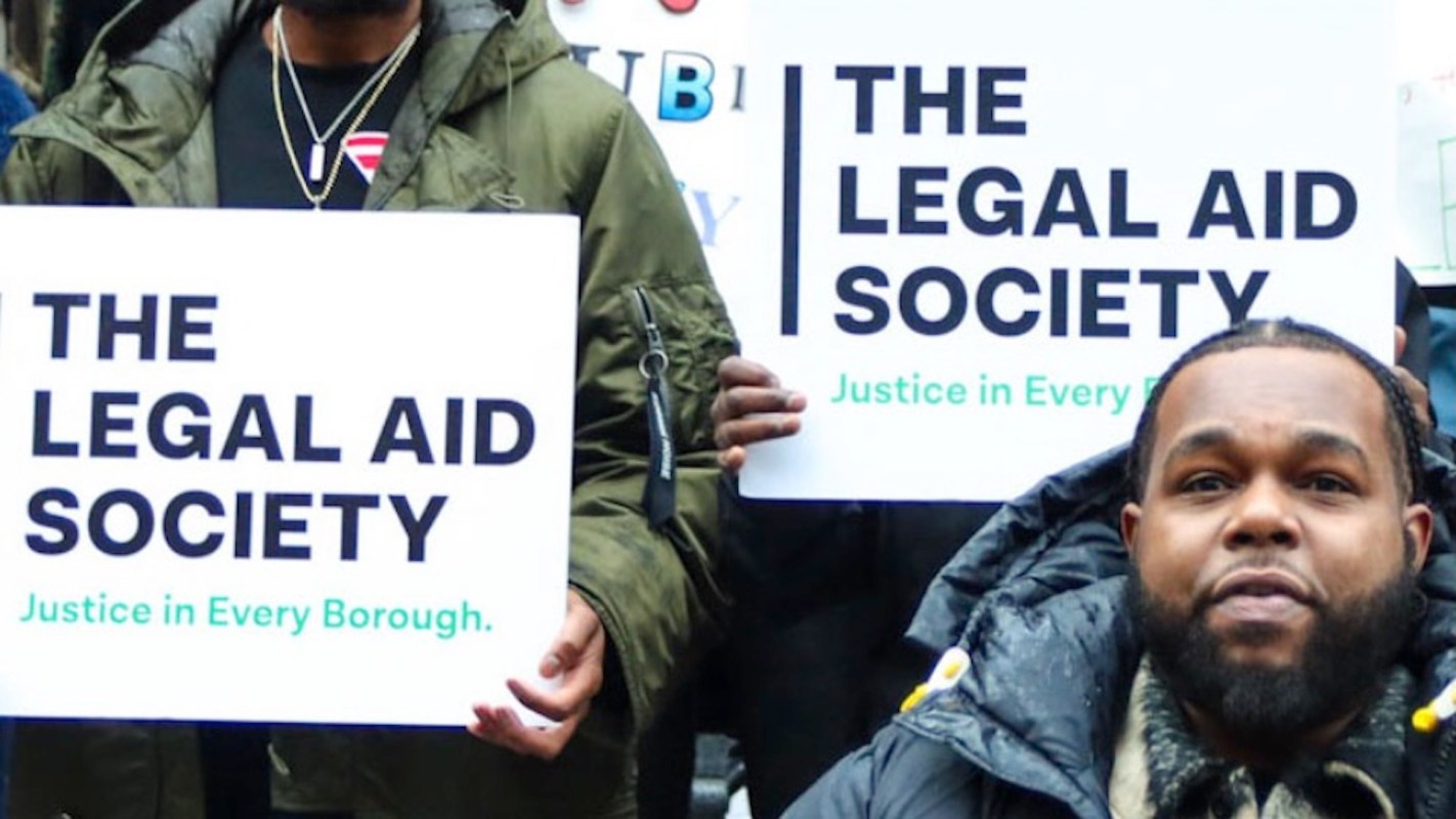 People holding signs that read "The Legal Aid Society" and "Justice in Every Borough."
