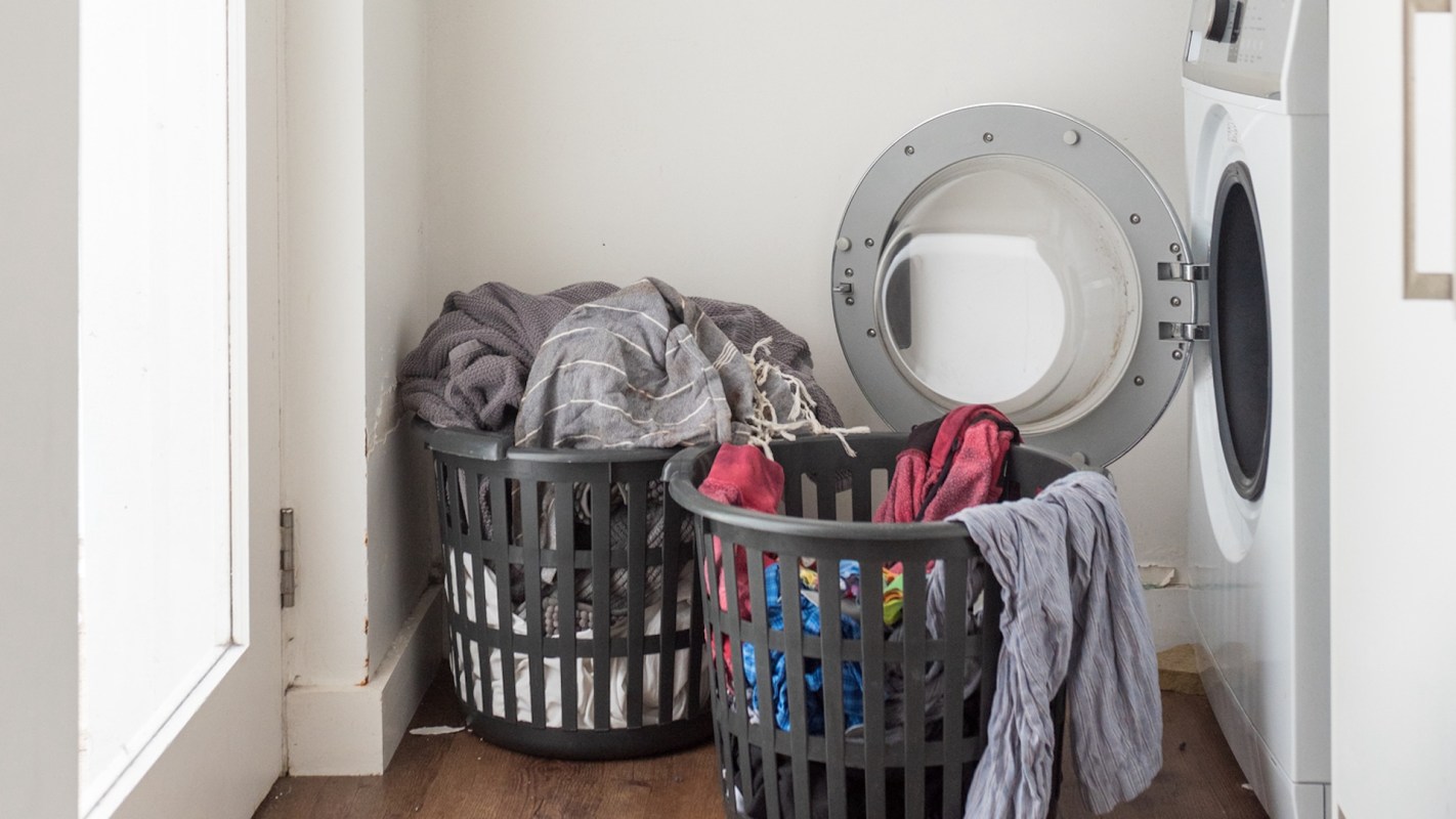 Two laundry baskets filled with clothes next to a washing machine.