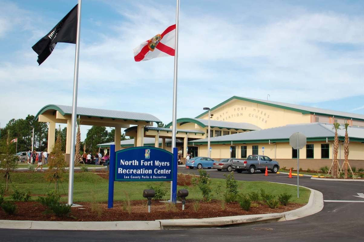 A recreation center in North Fort Myers with flags and visitors in the parking lot.