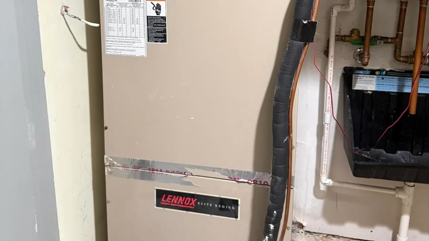 A Lennox Elite Series HVAC unit mounted on a wall with visible pipes and wires nearby.