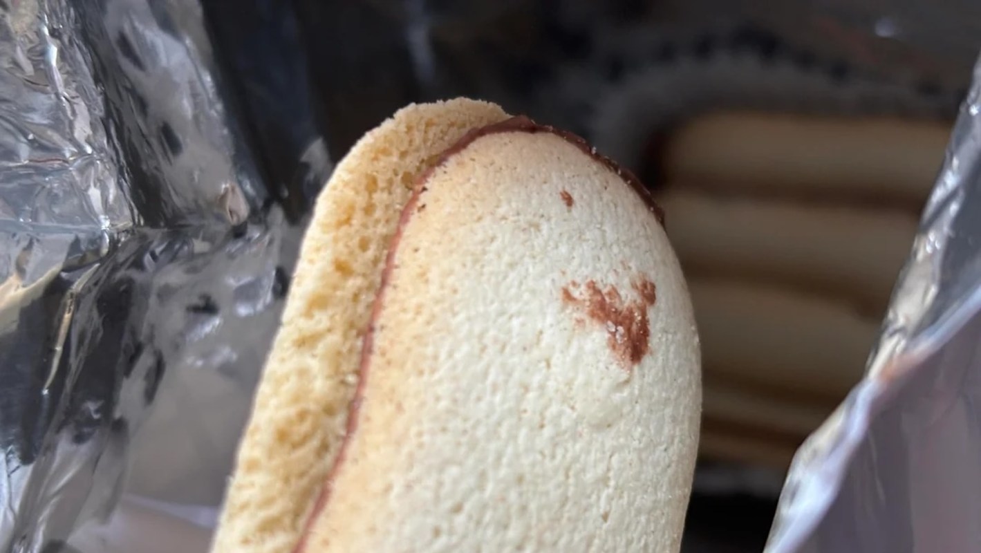 A cookie with a chocolate filling partially visible in a silver packaging.