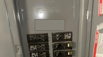 A circuit breaker panel with multiple circuit breakers and caution labels.