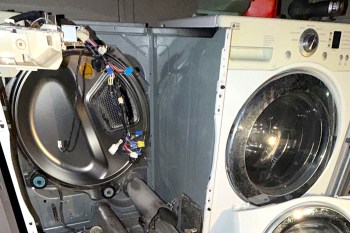 An open washing machine revealing internal components and wiring.