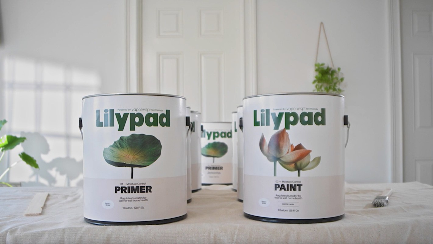 Several cans of paint labeled "Lilypad" and "Primer" are arranged on a table, with a paintbrush nearby.