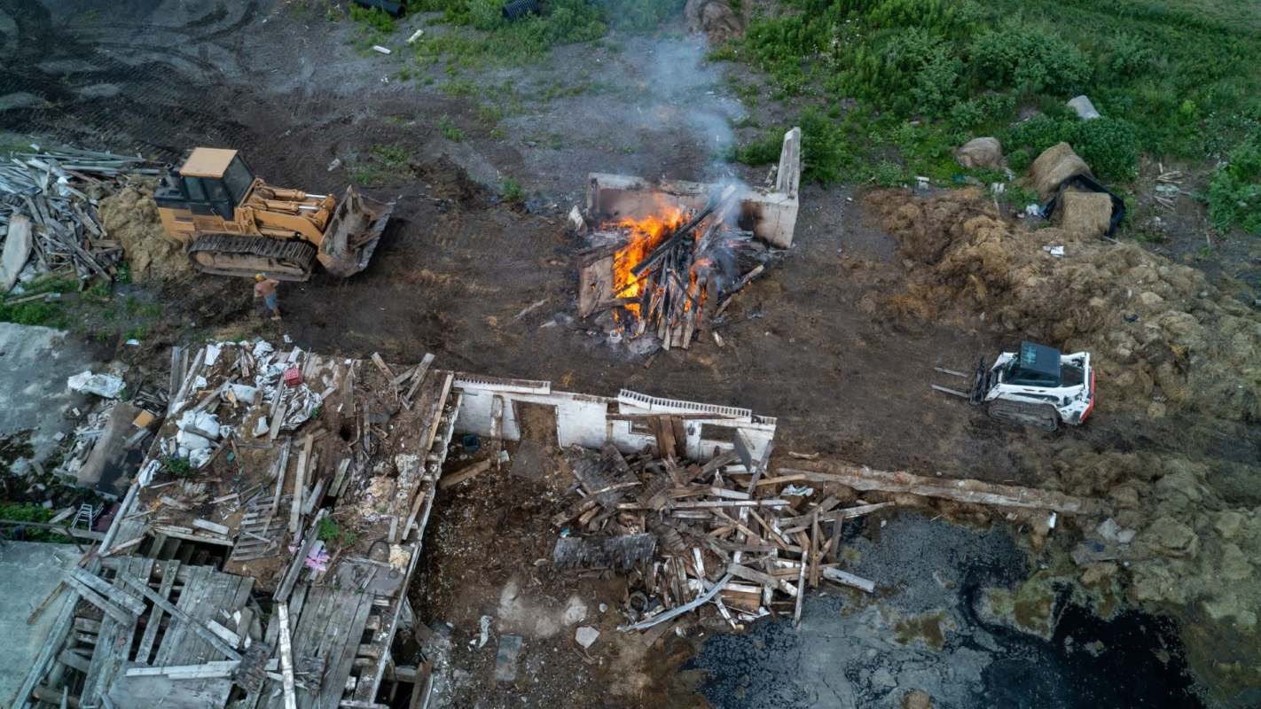 A construction site with a bulldozer, a burning pile of debris, and scattered rubble.