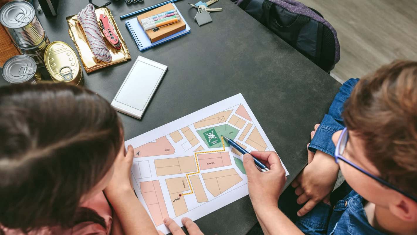Two people are analyzing an evacuation map on a table surrounded by various supplies and tools.