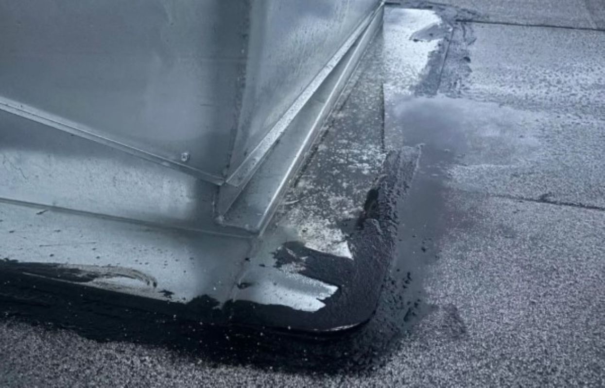 Water pooling around the base of a metal structure on a flat surface.