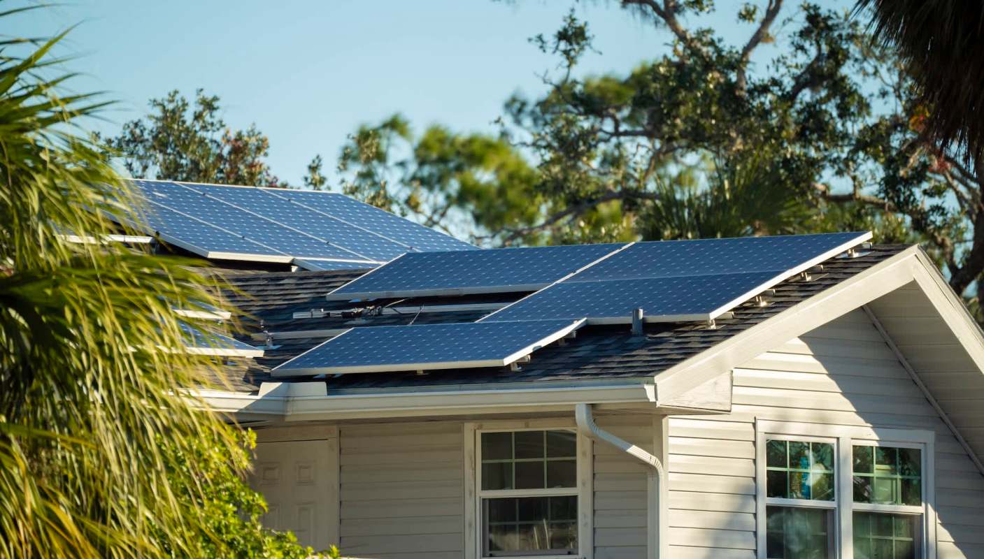 Solar panels installed on the roof of a house surrounded by trees.