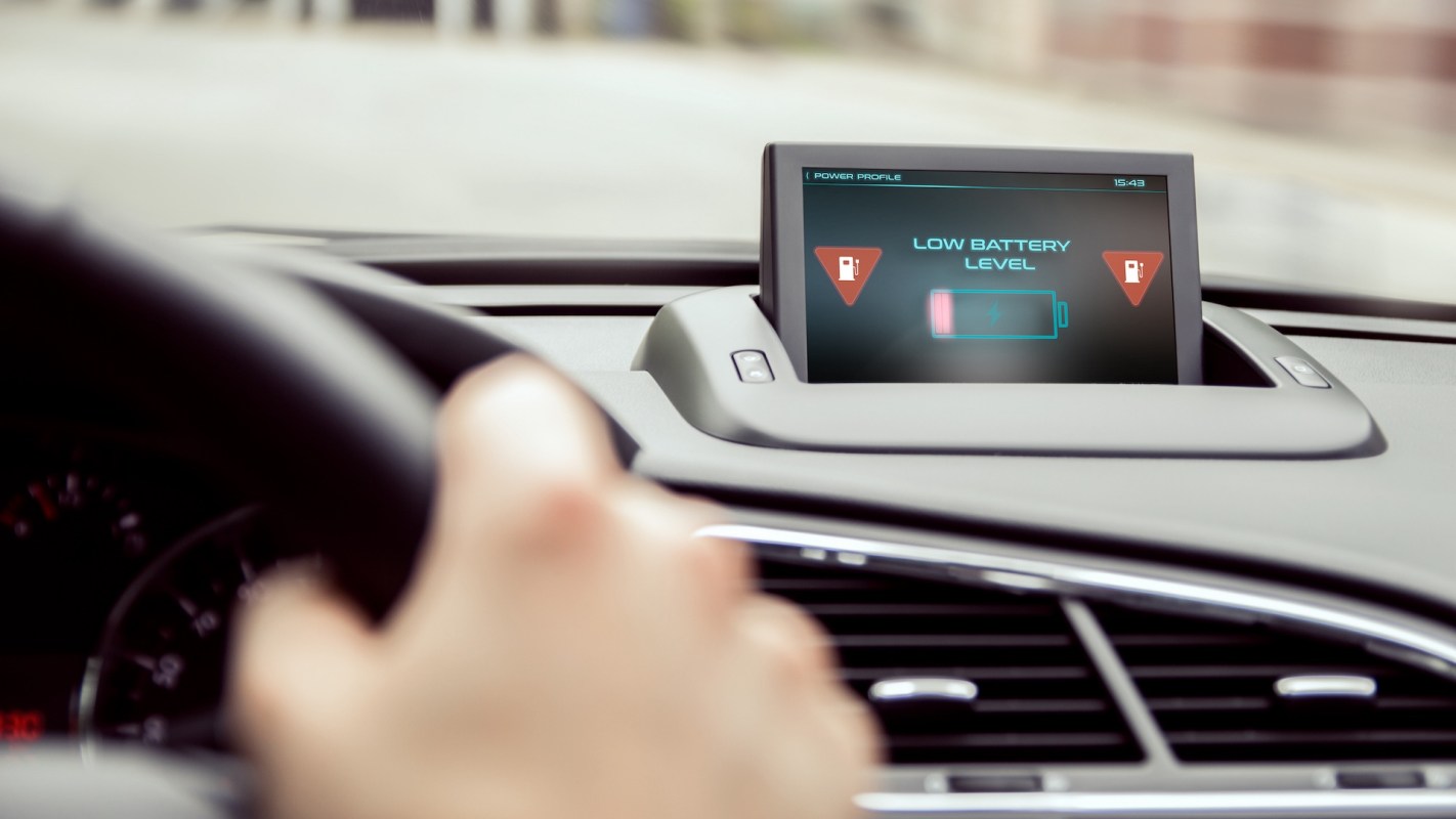 A car dashboard displaying a low battery level warning on the screen.