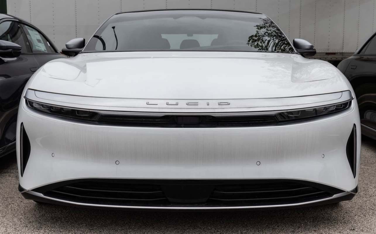 A white Lucid electric car parked between two other vehicles.