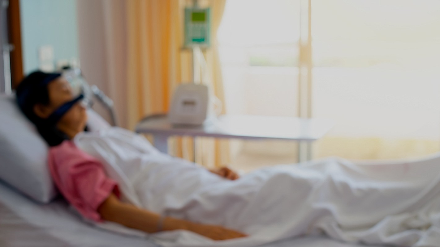 A patient lying in a hospital bed with medical equipment nearby.
