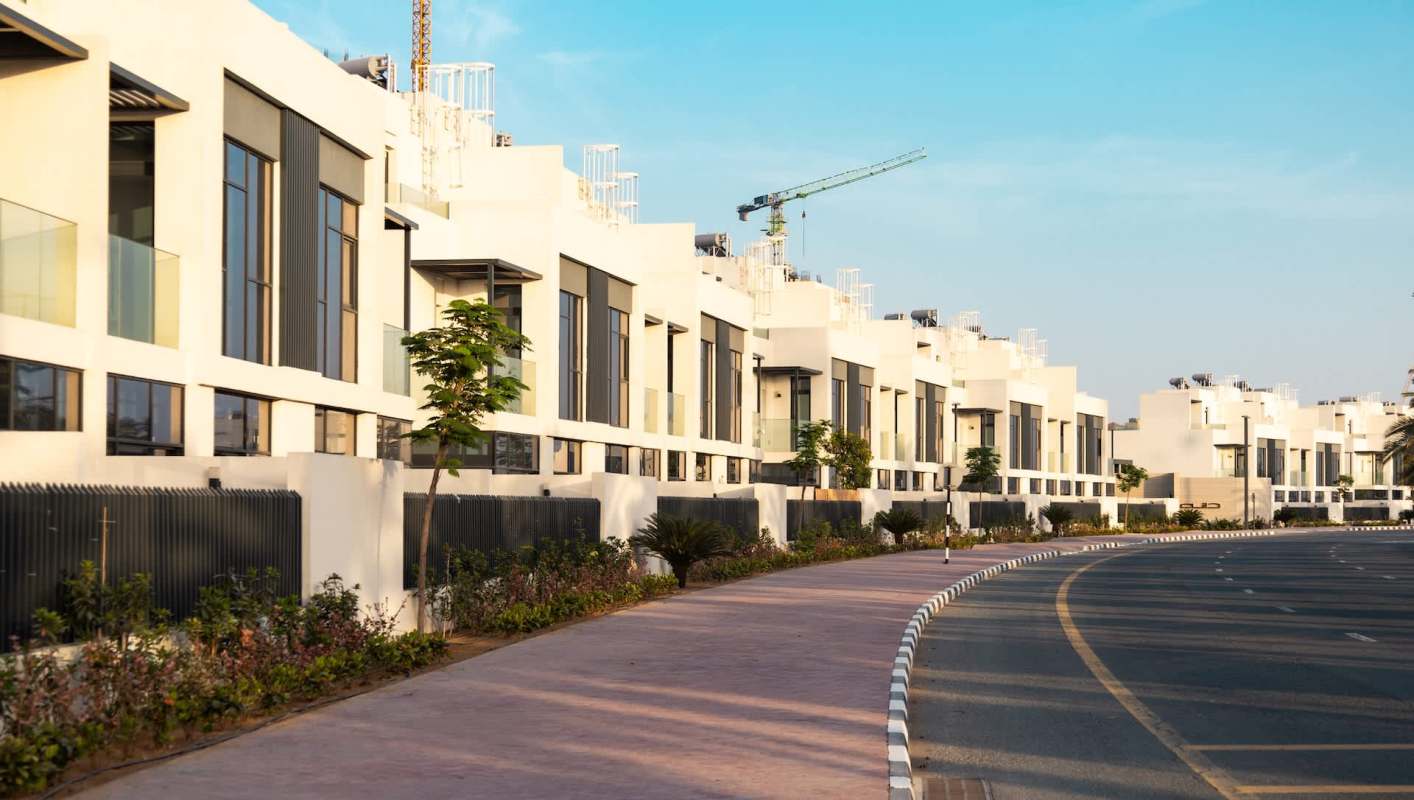 A row of modern white buildings along a curved pathway with greenery.