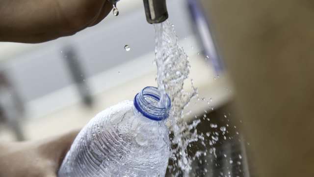 Water is being poured from a tap into a plastic bottle.