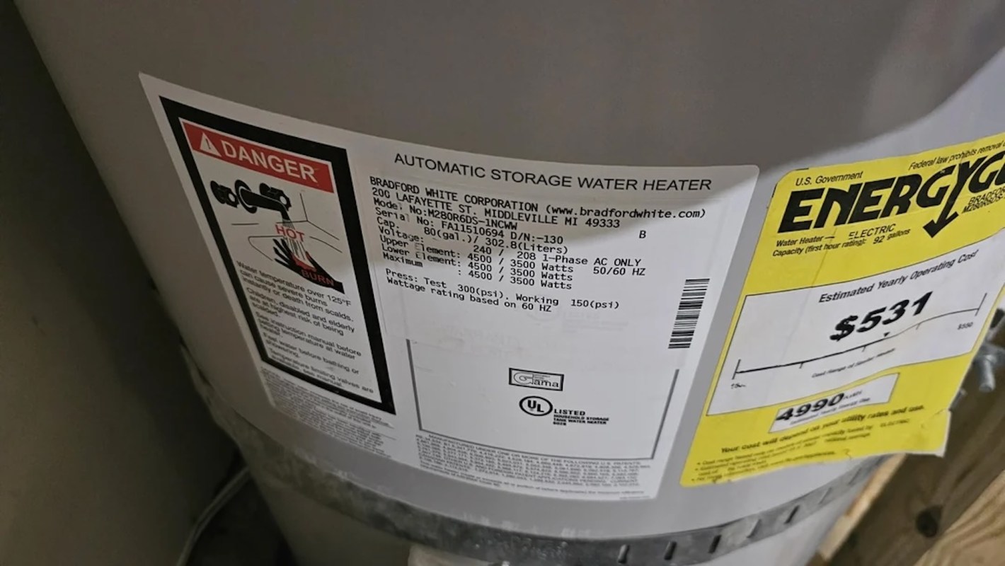 A water heater with warning labels and energy usage information attached.