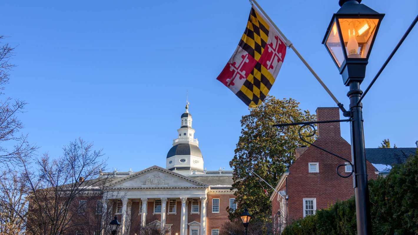 The Maryland State House with a flag and street lamp in the foreground.