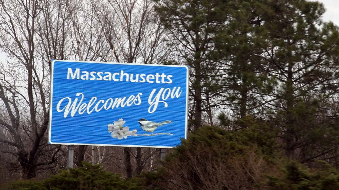 A welcome sign for Massachusetts featuring a bird and flowers.