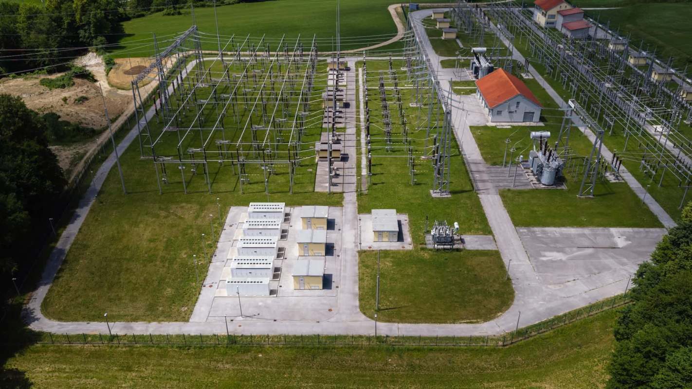 An aerial view of a power substation with various equipment and multiple electrical lines.