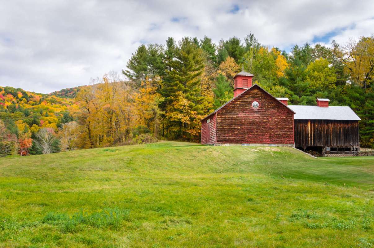 A red barn surrounded by grassy fields and colorful autumn trees.