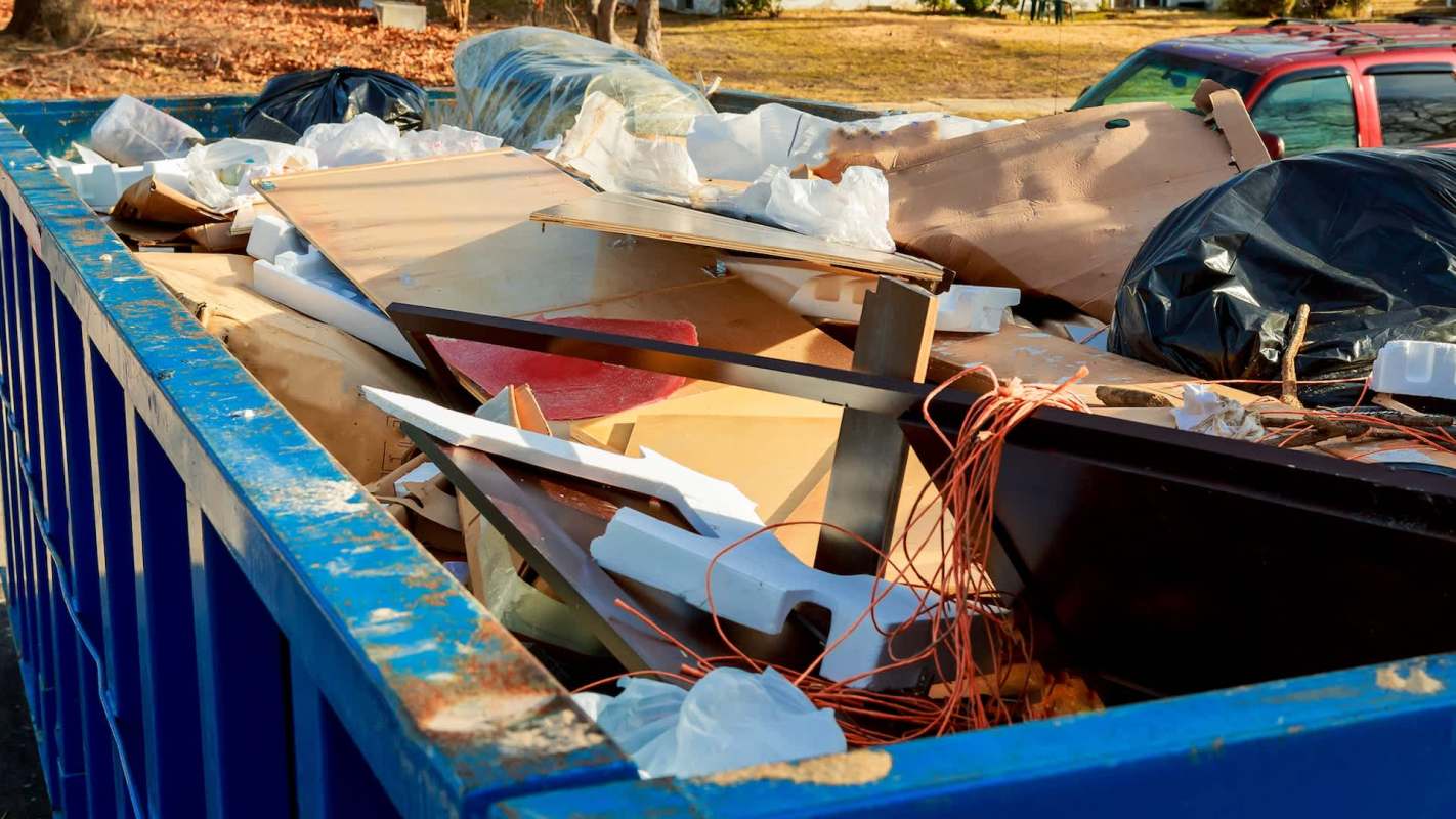 A dumpster filled with assorted construction debris, including wood, plastic, and metal scraps.