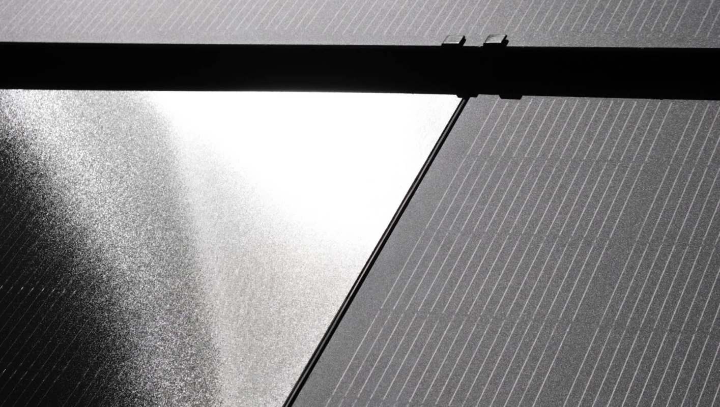 A partial view of solar panels reflecting light.