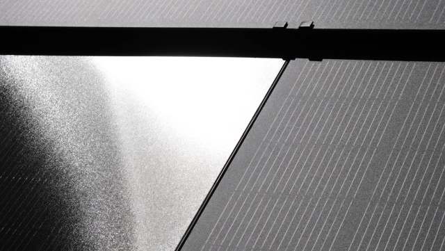 A partial view of solar panels reflecting light.