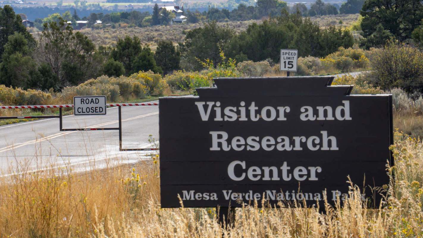 A sign for the Visitor and Research Center at Mesa Verde National Park, with a road closed sign nearby.