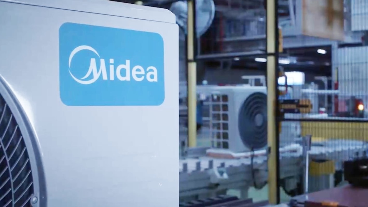 A Midea air conditioning unit in a factory setting with other machinery in the background.