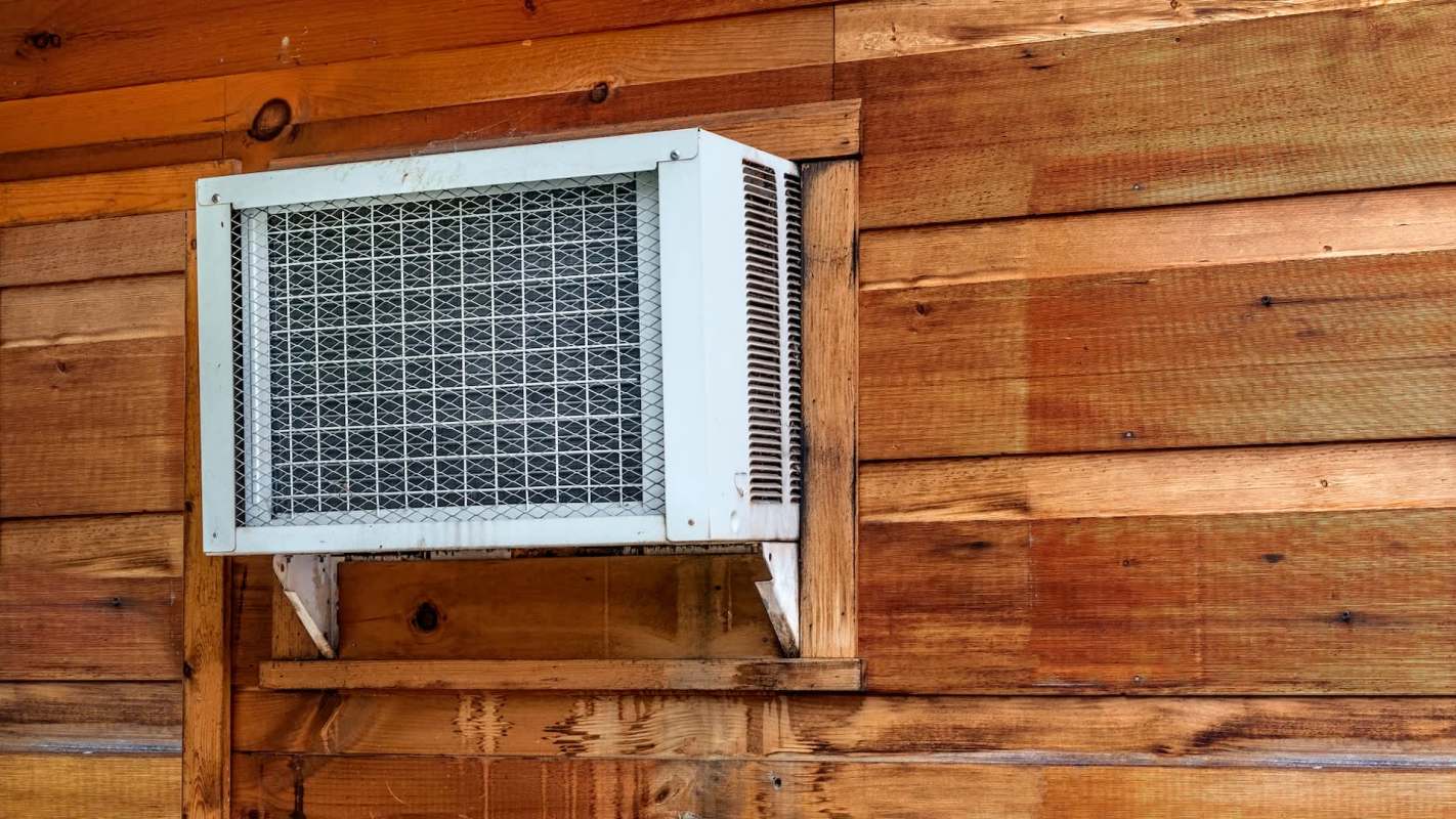 An air conditioning unit is mounted on a wooden wall.