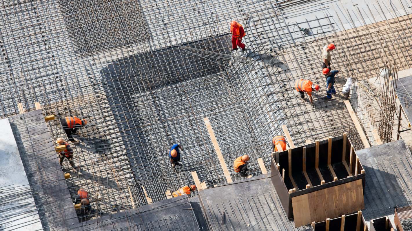 Construction workers are installing steel rebar on a building site.