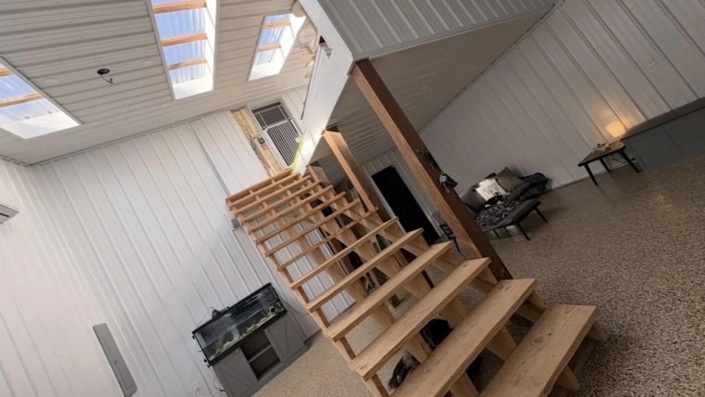 An interior space featuring wooden stairs, a fish tank, and a seating area with a lamp.