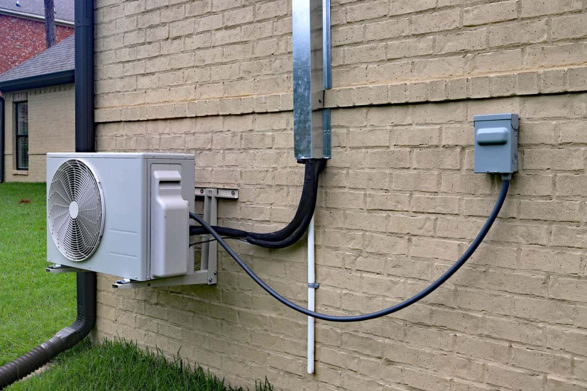 A mini split system attached to a brick home.