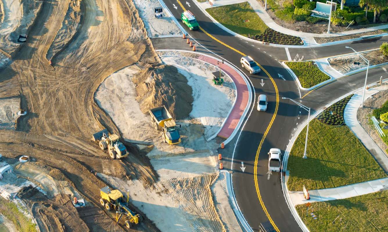 Aerial view of a construction site with heavy machinery and vehicles on a road under development.