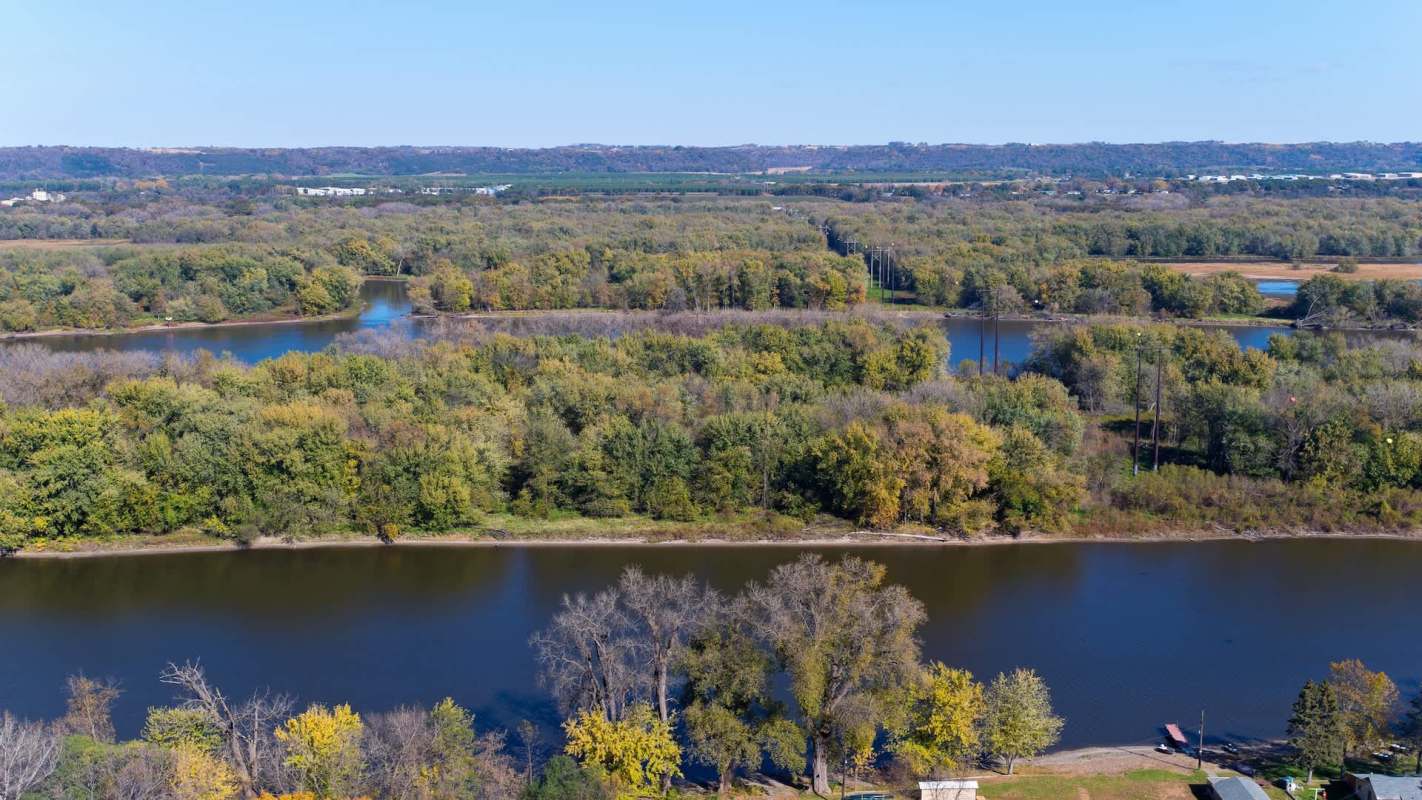A river meanders through a landscape of trees and greenery under a clear blue sky.