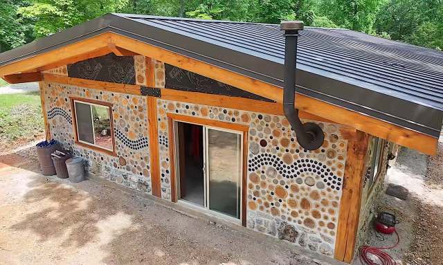 A rustic building with a stone exterior and wooden accents surrounded by trees.
