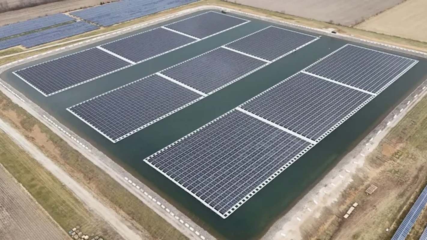 A solar panel installation on a body of water with fields in the background.