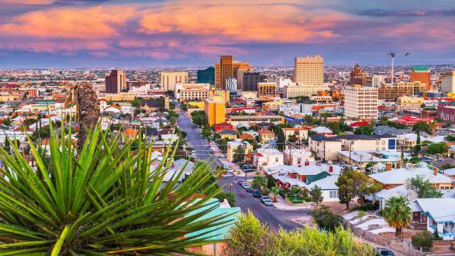 A view of the El Paso, Texas, city skyline with buildings and houses under a colorful sky.