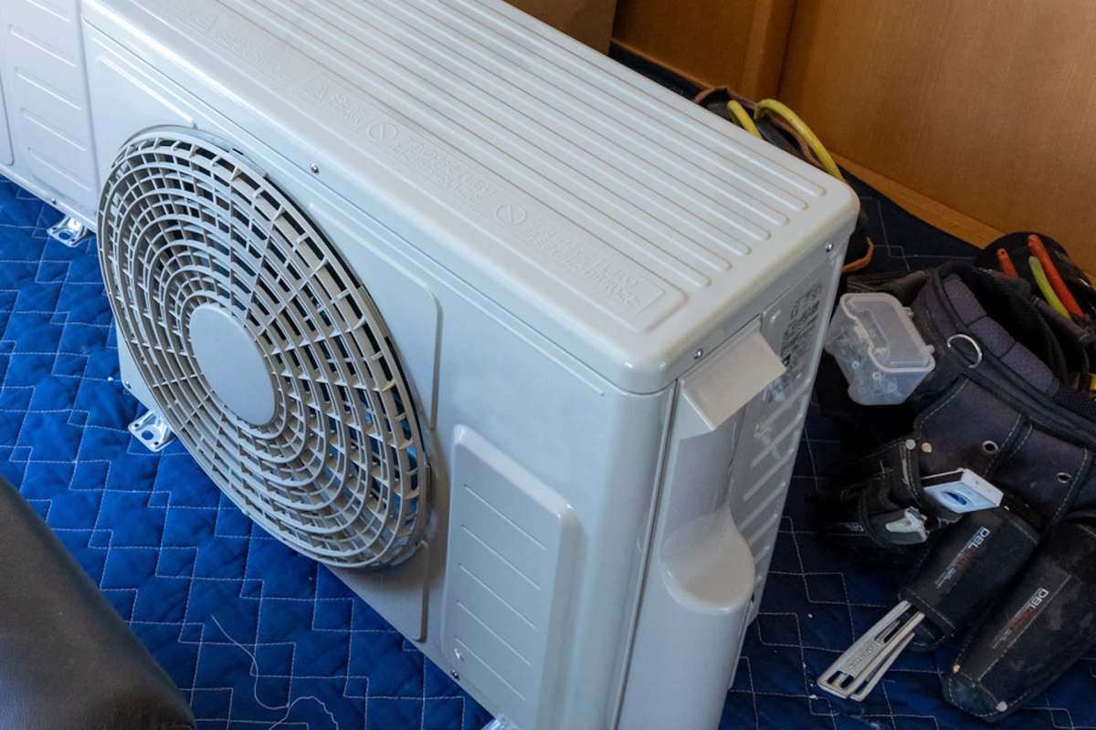 An air conditioning unit on a padded surface with tools and equipment nearby.