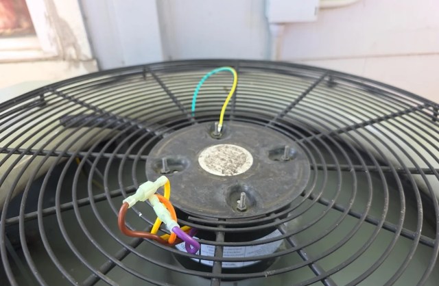 A outdoor fan unit with colorful electrical wires connected to its base.