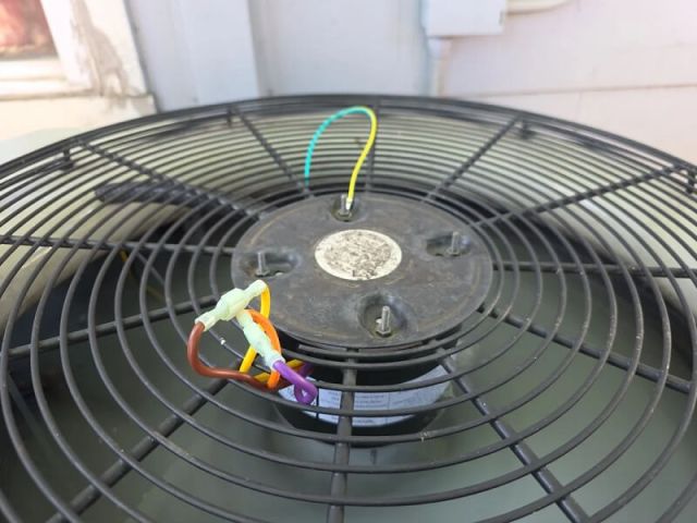 A outdoor fan unit with colorful electrical wires connected to its base.